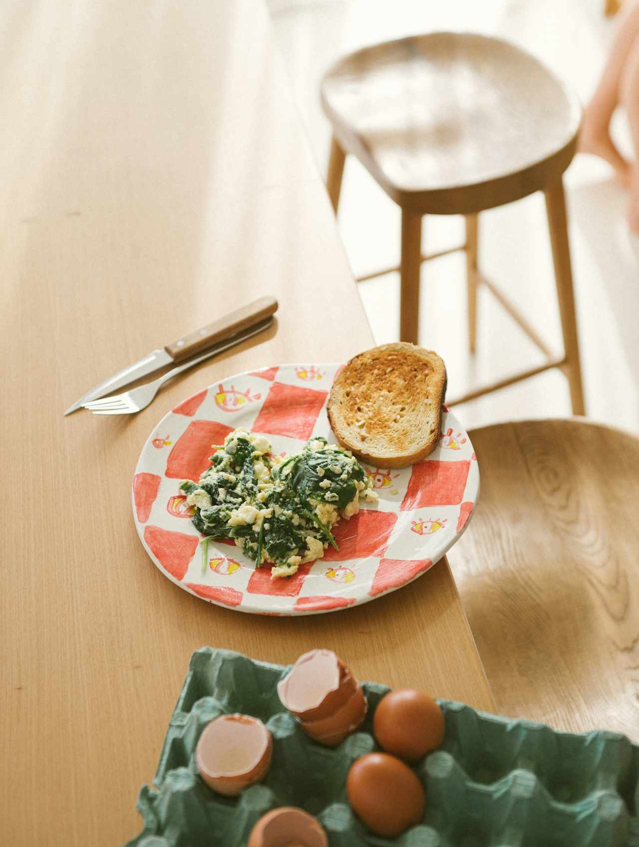 A sunlit kitchen featuring a plate with a breakfast sandwich.